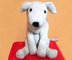 a white stuffed dog sitting on top of a red table