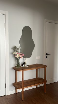 a wooden bench sitting in front of a mirror on the wall next to a vase with flowers