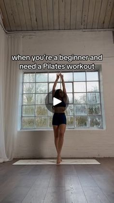 a woman doing yoga in front of a window with the words when you're a beginner and need a pilates workout