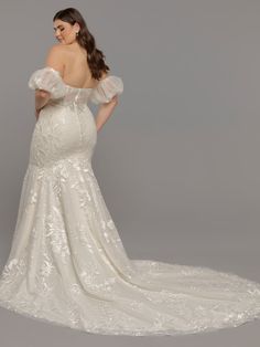 a woman in a wedding dress with an off the shoulder neckline and ruffled sleeves