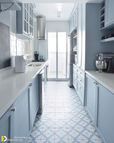 a kitchen with blue cabinets and white counter tops, along with an open door leading to the outside