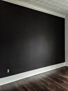 an empty room with black walls and wood floors