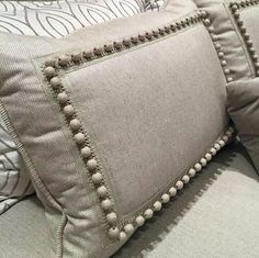 a close up of a couch with pillows on it's sides and one pillow that has pom - poms