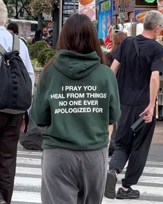 a woman wearing a green hoodie that reads, i pray you heal from things no one ever applied for