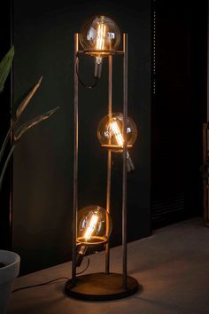 a lamp that is sitting on top of a wooden stand next to a potted plant