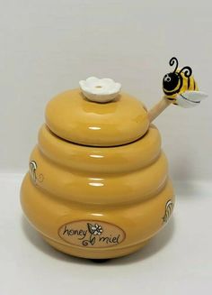 a yellow ceramic honey pot with a bee on top