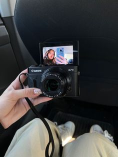 a person holding up a camera in the back seat of a car with their feet on the floor