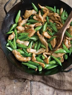 chicken and green beans in a skillet with a wooden spoon