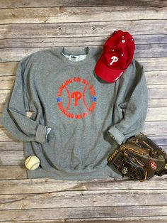 The Phillies have danced their way into the World Series! This sweatshirt will help you show your team spirit! The graphic has the words Dancing on My Own in a circle with baseball stitches and the Phillies P in the middle. The colors are Phillies Red and Blue. The sweatshirt is a grey unisex sweatshirt that is super soft on the inside and runs true to size.  I will turn these orders around ASAP as I know these are time sensitive. I am local to Philly and live in South Jersey and all orders will Cheerleading Fan Apparel Sweatshirt With Graphic Print, Cheerleading Sweatshirt With Graphic Print For Sports Season, Cheerleading Letter Print Crew Neck Sweatshirt, Crew Neck Sweatshirt With Letter Print For Cheerleading, Letter Print Sweatshirt For Cheerleading, Phillies Shirt, Dancing On My Own, Baseball Stitch, My Own