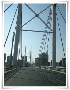 a car driving across a bridge with tall buildings in the backgrounnds