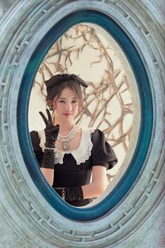 a woman in a black and white dress is looking through a round window