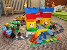 a toy train set sitting on top of a carpeted floor next to a child's bed