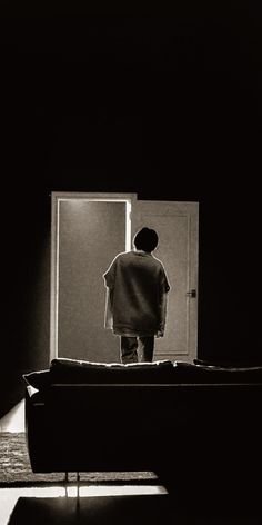 a man standing in front of an open door with his back turned to the camera