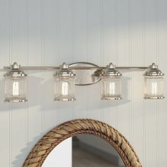 a bathroom vanity light with three lights and a rope hanging from the wall next to it