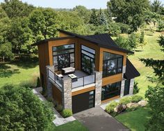 an aerial view of a house in the middle of some trees and grass with lots of windows