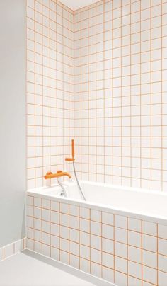 an orange and white tiled bathroom with a bathtub, faucet and shower head