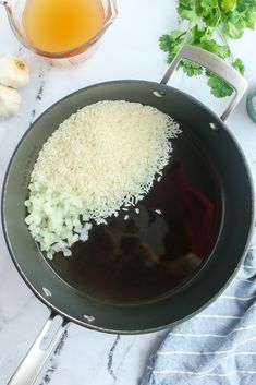 rice is being cooked in a wok on the counter next to garlic and cilantro