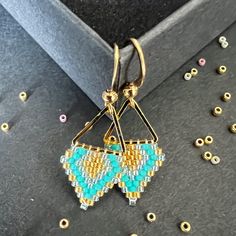 You can choose between silver color (silver plated brass) or gold (gold plated brass) triangular hoop link of size 12mm and earring hook of size . Color: Gold, turquoise, light sea foam Miyuki DB  These earrings epitomize craftsmanship, utilizing top-tier branded beads such as Miyuki Delica beads and TOHO seed beads. Meticulously handcrafted with a robust beading thread, these earrings guarantee enduring shape retention and bead stability, even with continuous wear. A diverse spectrum of color combinations is available to cater to individual preferences, while all metallic components are expertly fashioned from high-quality brass. Hypoallergenic earring hooks prioritize wearer comfort and safety. Each design in the shop reflects a profound commitment to artistry, characterized by painstaki Handmade Geometric Gold Earrings, Gold Beaded Geometric Earrings, Geometric Beaded Gold Earrings, Gold Geometric Beaded Earrings As A Gift, Gold Geometric Beaded Earrings For Gift, Gold Geometric Beaded Earrings, Geometric Gold Beaded Earrings, Handmade Minimalist Geometric Jewelry, Minimalist Handmade Geometric Jewelry