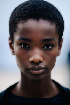 a close up of a person wearing a black shirt and short hair with an afro