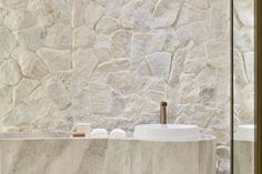 a white sink sitting next to a stone wall