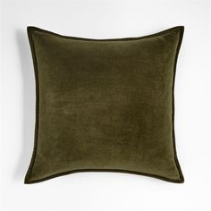 a dark green velvet pillow on a white wall with a black border around the edges