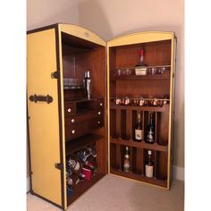 an open cabinet with liquor bottles and other items in the bottom shelf, on carpeted flooring