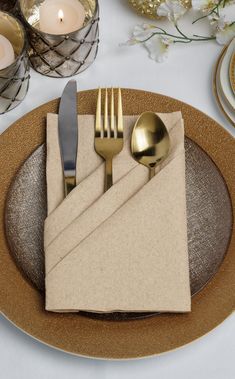 a place setting with silverware and napkins on a gold - plated table