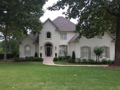 a large white house sitting in the middle of a lush green field