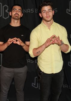 two men standing next to each other in front of a black background