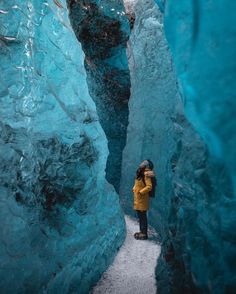 a person standing in the middle of an ice cave, surrounded by large blue rocks