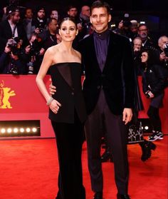 a man and woman standing next to each other on a red carpet at an event