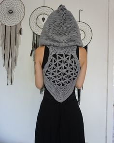 a woman wearing a crochet hat and black dress standing in front of three dream catchers