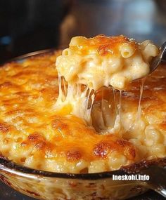 a spoon full of macaroni and cheese being lifted from a casserole dish