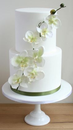 a three tiered cake with white flowers on top