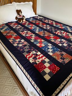 a bed with a quilt on it and a teddy bear