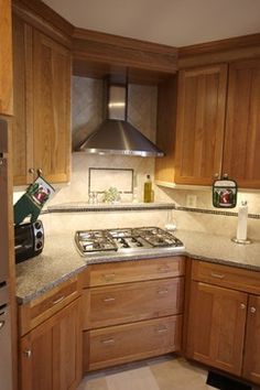 a kitchen with wooden cabinets and granite counter tops, including a stove top oven in the corner