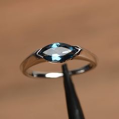 It is a London blue topaz ring. The main stone is 5 mm* 10 mm marquise cut.weight about 1.24 carats. The basic metal is sterling silver and plated with rhodium. To change the metal to a solid gold (white/rose) or platinum is also available, please ask for a quotation if you want. You can also go to my shop Home for more elegant rings: https://www.etsy.com/shop/godjewelry?ref=hdr_shop_menu London blue topaz is November birthstone More London blue topaz rings: https://www.etsy.com/shop/godjewelry? East To West Engagement Ring, Topaz Wedding Ring, Blue Topaz Engagement Ring, Blue Gemstone Rings, Ring Marquise, London Blue Topaz Ring, Sterling Silver Engagement Rings, Blue Gems, Silver Engagement Rings