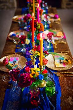 a long table is decorated with colorful flowers and candles for a festive dinner party