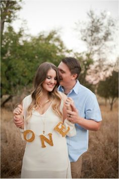 a man and woman standing next to each other in front of some tall brown grass