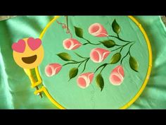 an embroidery project with flowers and a smiley face in the center on a green background