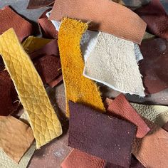 several different types of leathers are on the floor with one yellow piece in the middle