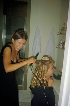 a woman blow drying her daughter's hair in the bathroom