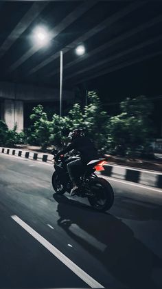 a person riding a motorcycle on a city street at night with the lights turned on