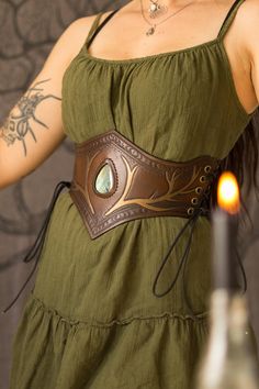 Pagan Enchantress leather corset belt A leather corset belt that will enhance your curves beautifully. The stone is a gorgeous labradorite, often said to have magical properties. There are two bind runes on this belt, one on each back panel. They stand for creation & protection.  This corset is made from a thick quality leather that will last you a lifetime. The colour is a rich brown with bronze hardware and linework. Size: 65cm (will fit a 65 to 75cm waist) *model has a 73cm waist and is 172cm tall. If you have any questions about the size, details etc, feel free to ask. If you wish to have something similar in a different size, colour or other customisation, feel free to message me! Corset Belt Outfit, Bind Runes, Leather Corset Belt, Brown Corset, Ren Fest, Waist Corset, Corset Belt, Bronze Hardware, Leather Corset