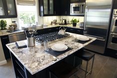 a kitchen with granite counter tops and stainless steel appliances, along with black cabinetry