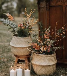 two baskets filled with flowers and candles sitting on the ground next to each other in front of a wooden cabinet