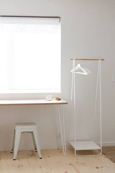 an empty room with a desk, stool and window