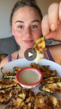 a woman is eating an appetizing dish with cheese and sauce on the plate