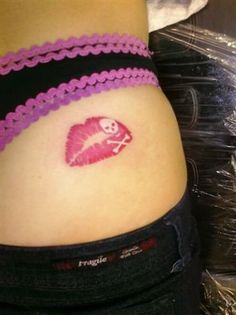 a woman's stomach with a pink heart tattoo on the side of her belly