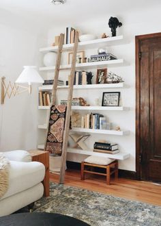 a living room filled with furniture and bookshelves next to a wooden door in front of a white wall